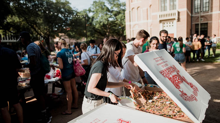 Grad students eat pizza in the graduate commons outside Valhalla