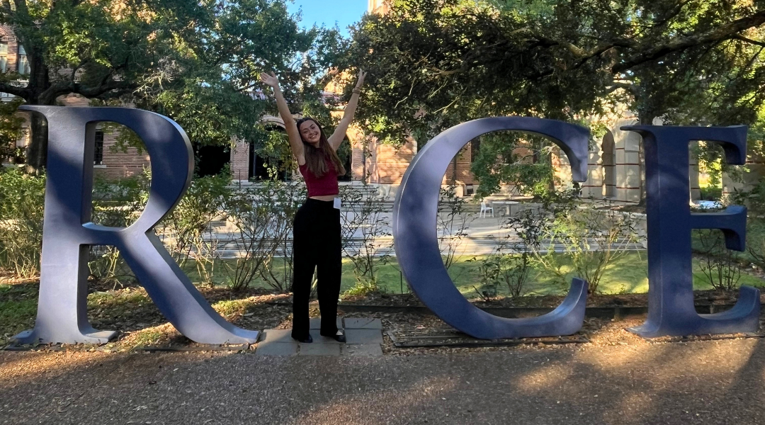 Olivia Beddow on campus at the Rice sign in front of the Welcome Center