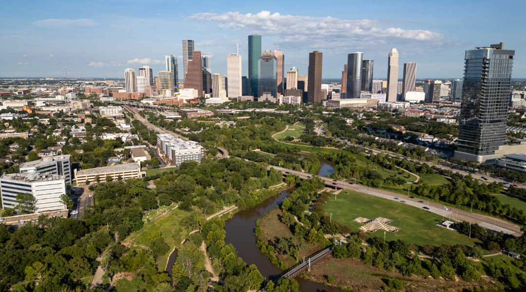 An aerial photo of Buffalo Bayou with the skyline of Downtown Houston in background