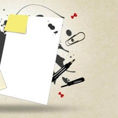 Collection of papers, pencils, paperclips and an ink spill splashed on a tan background