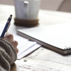 Student writing at a desk