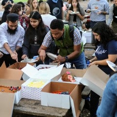 Students descend on their award cakes in the Grad Commons for GPS' Take the Cake