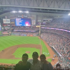 three people standing in the bleachers of a baseball stadium 