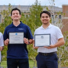 Graduate student pose in the quad with their awards