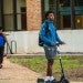 Student riding on a scooter on Rice's campus.
