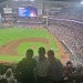 three people standing in the bleachers of a baseball stadium 